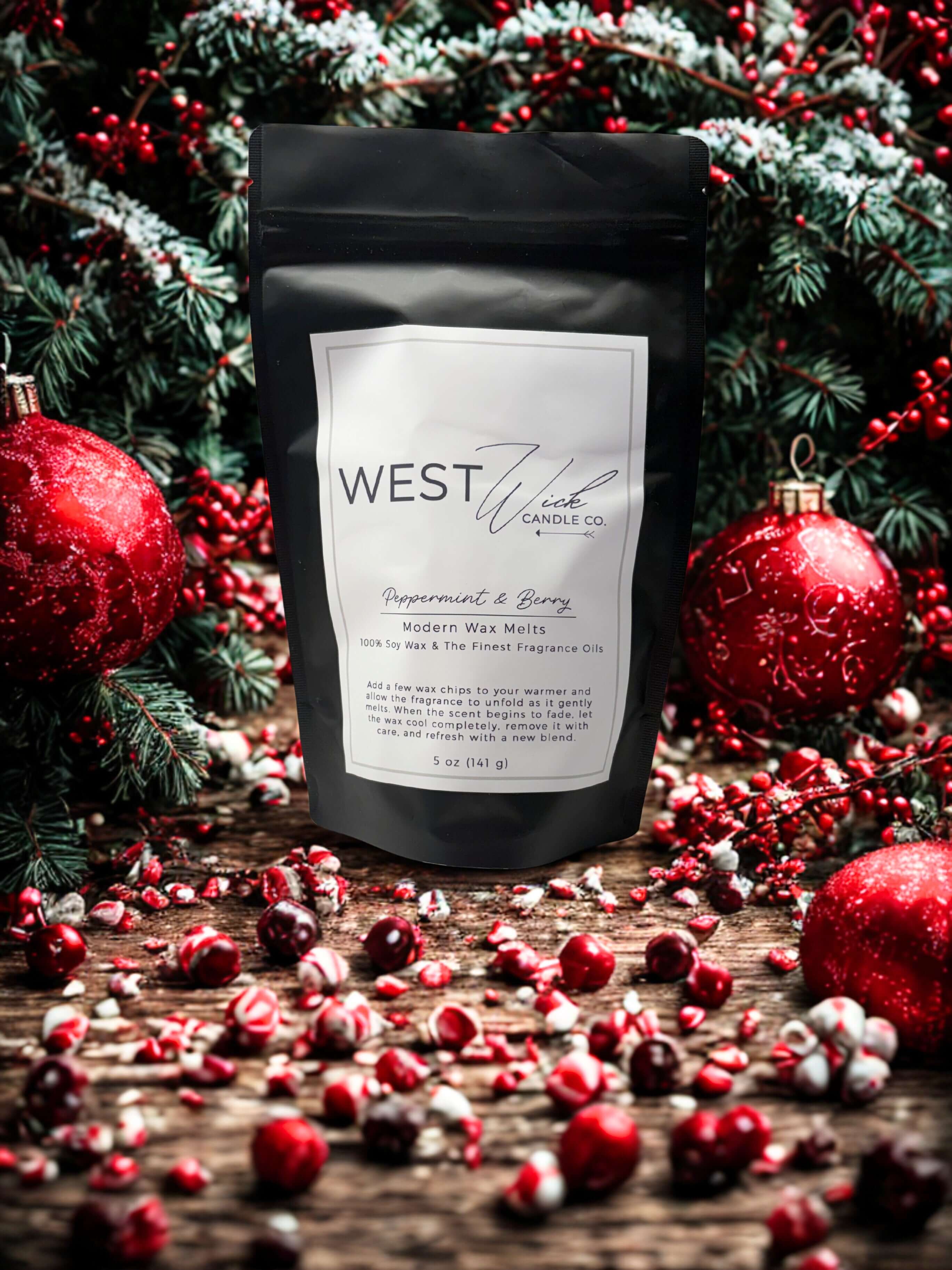 Peppermint & Berry Wax Melts packaging by West Wind Candle Co, surrounded by festive decorations and greenery.