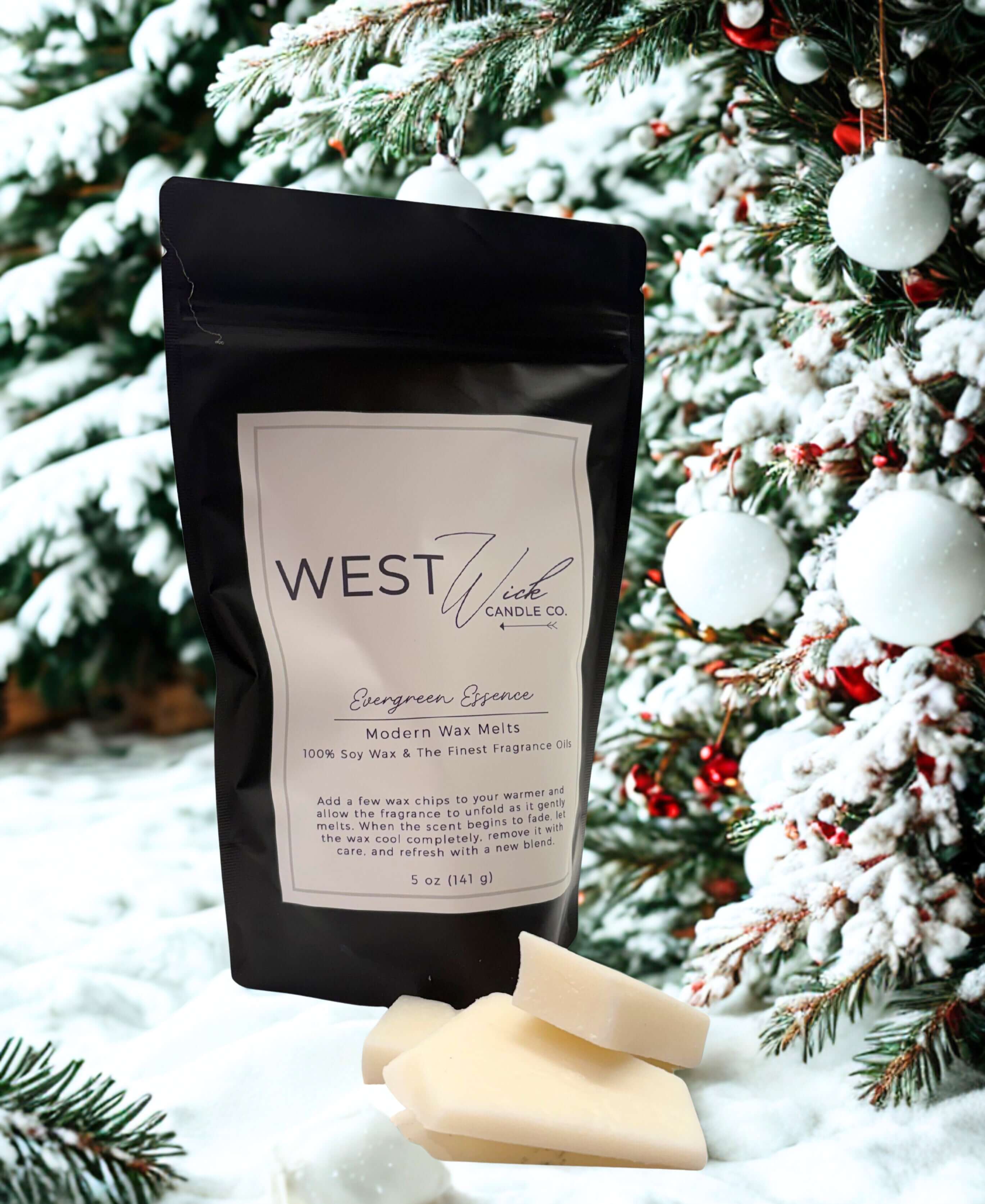 Evergreen Essence Wax Melts packaging displayed in a snowy evergreen forest setting with wax melts in front.