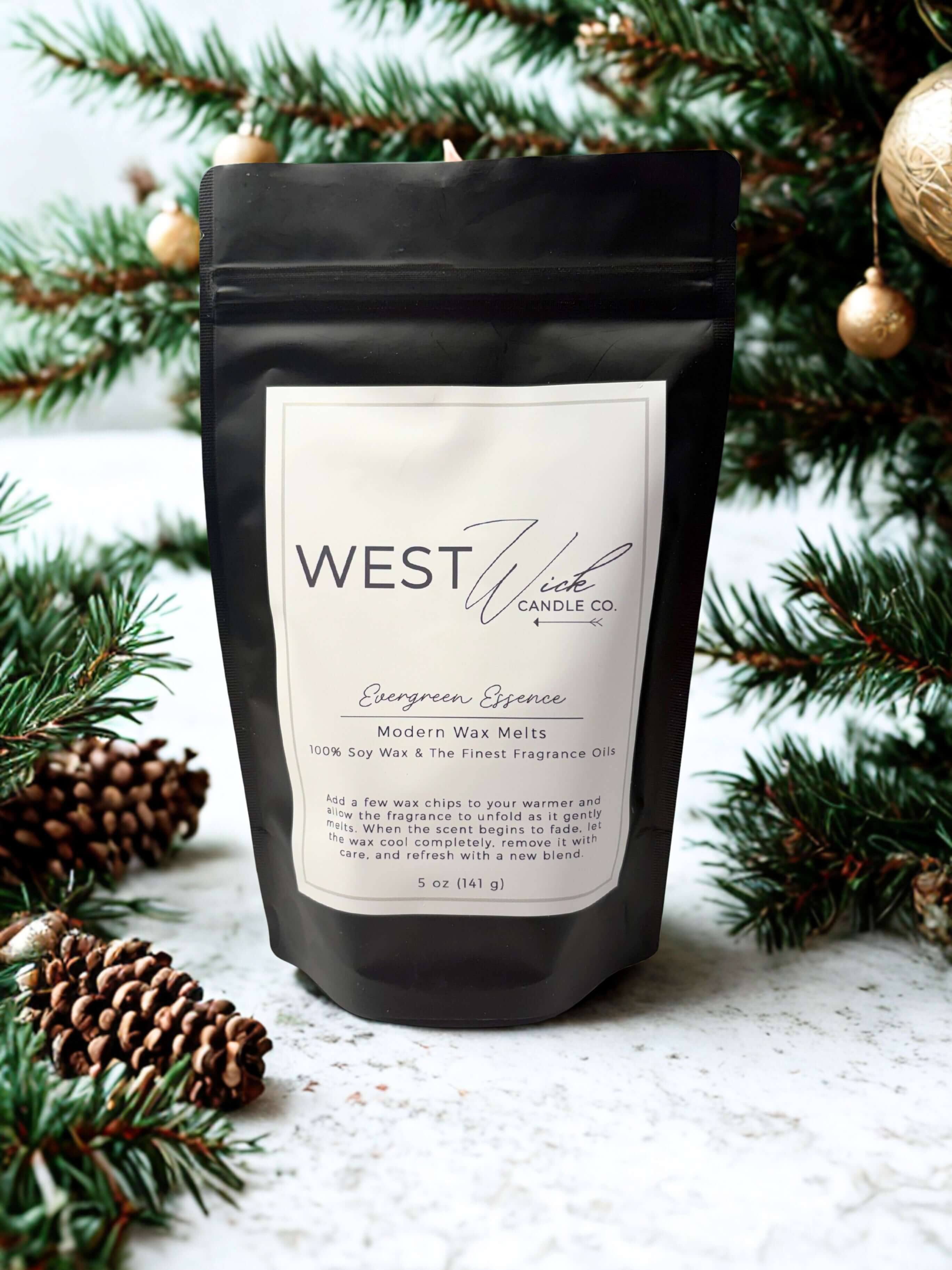 Evergreen Essence Wax Melts by WEST WILD Candle Co in a black pouch with festive pine branches.