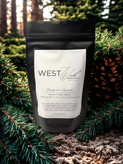 Evergreen Essence Wax Melts pouch displayed among snowy evergreen trees and pinecones.