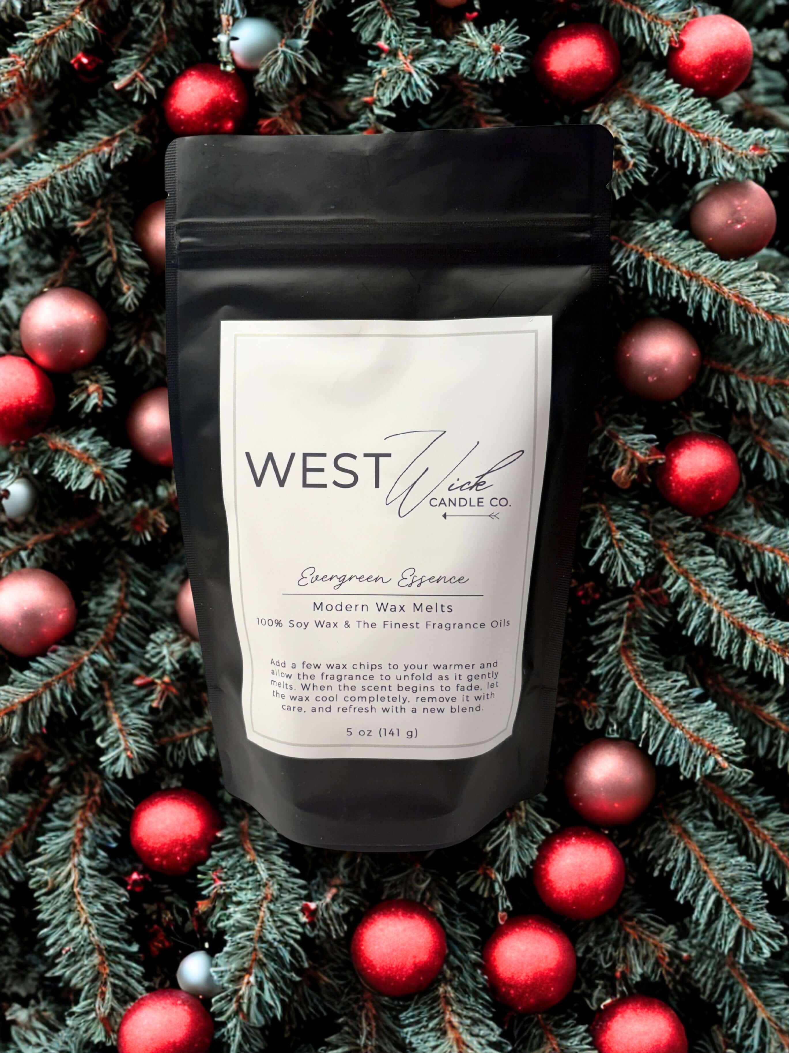 Evergreen Essence Wax Melts by West Willow Candle Co. displayed on a festive background of pine and ornaments.