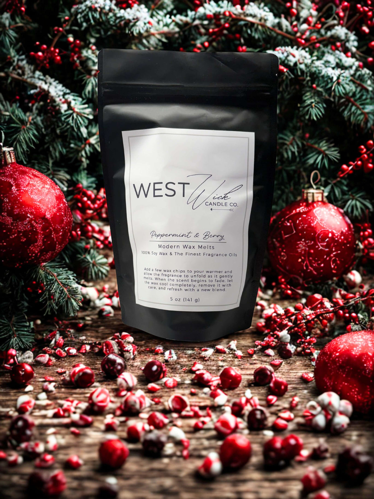 Peppermint &amp; Berry Wax Melts packaging by West Wind Candle Co, surrounded by festive decorations and greenery.