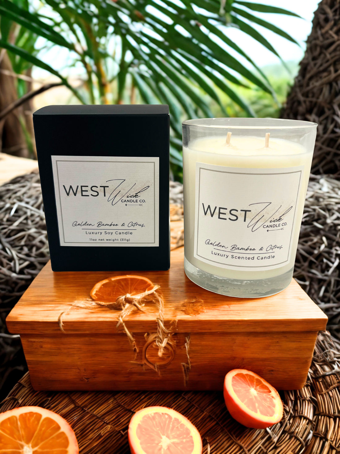 West Wick candle with packaging on a wooden box with oranges and greenery in the background