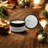 Evergreen Essence - Black Luxe Candle with two wicks, surrounded by festive decorations and warm holiday ambiance.