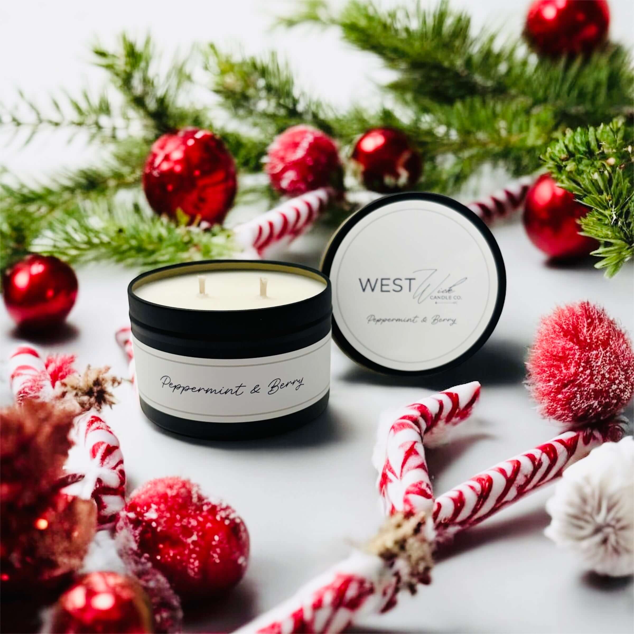 Peppermint &amp; Berry Black Luxe Candle surrounded by festive decor and greenery, inviting seasonal warmth.