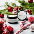 Peppermint & Berry Black Luxe Candle surrounded by festive decor and greenery, inviting seasonal warmth.