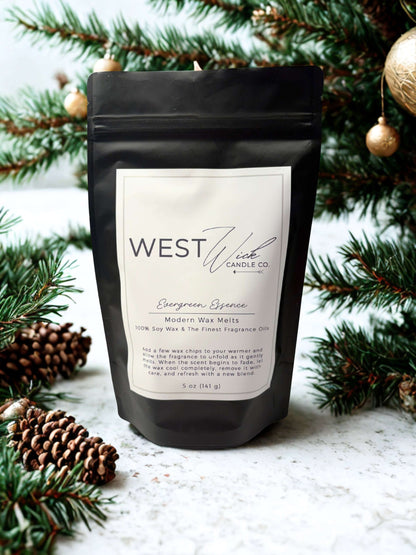 Evergreen Essence Wax Melts by WEST WILD Candle Co in a black pouch with festive pine branches.